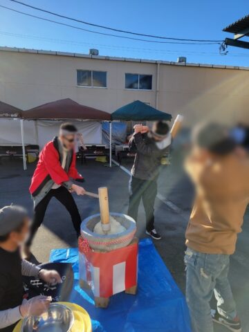 法被を着た人が臼の餅を杵でつく様子