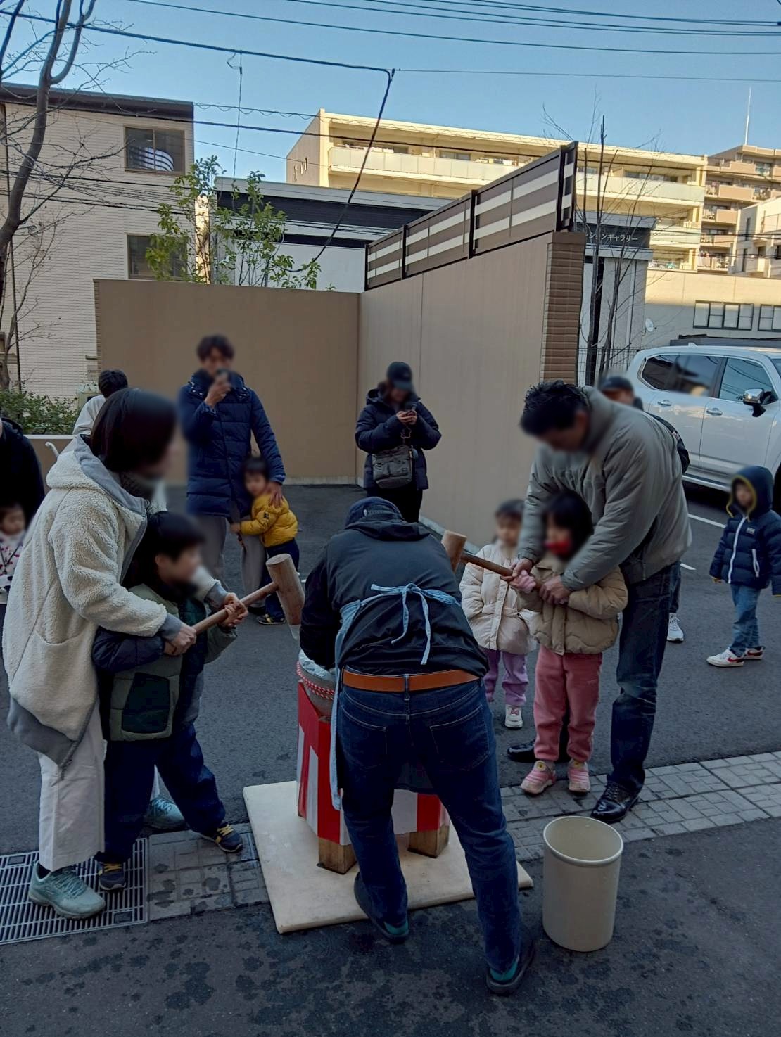 家族連れが順番に杵を持って餅をつく屋外の餅つき
